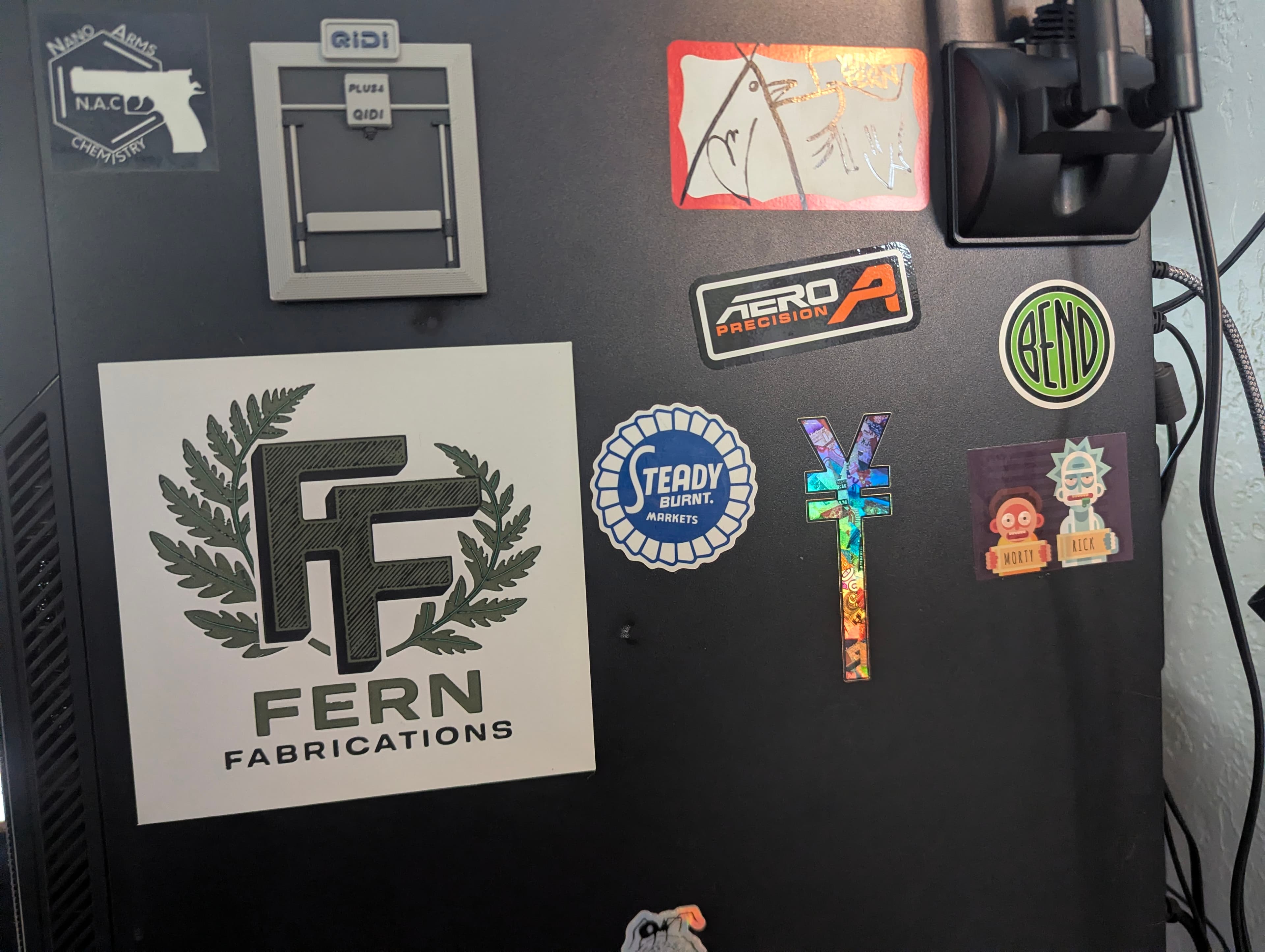 Fern Fabrications logo magnet on a computer alongside other brand magnets