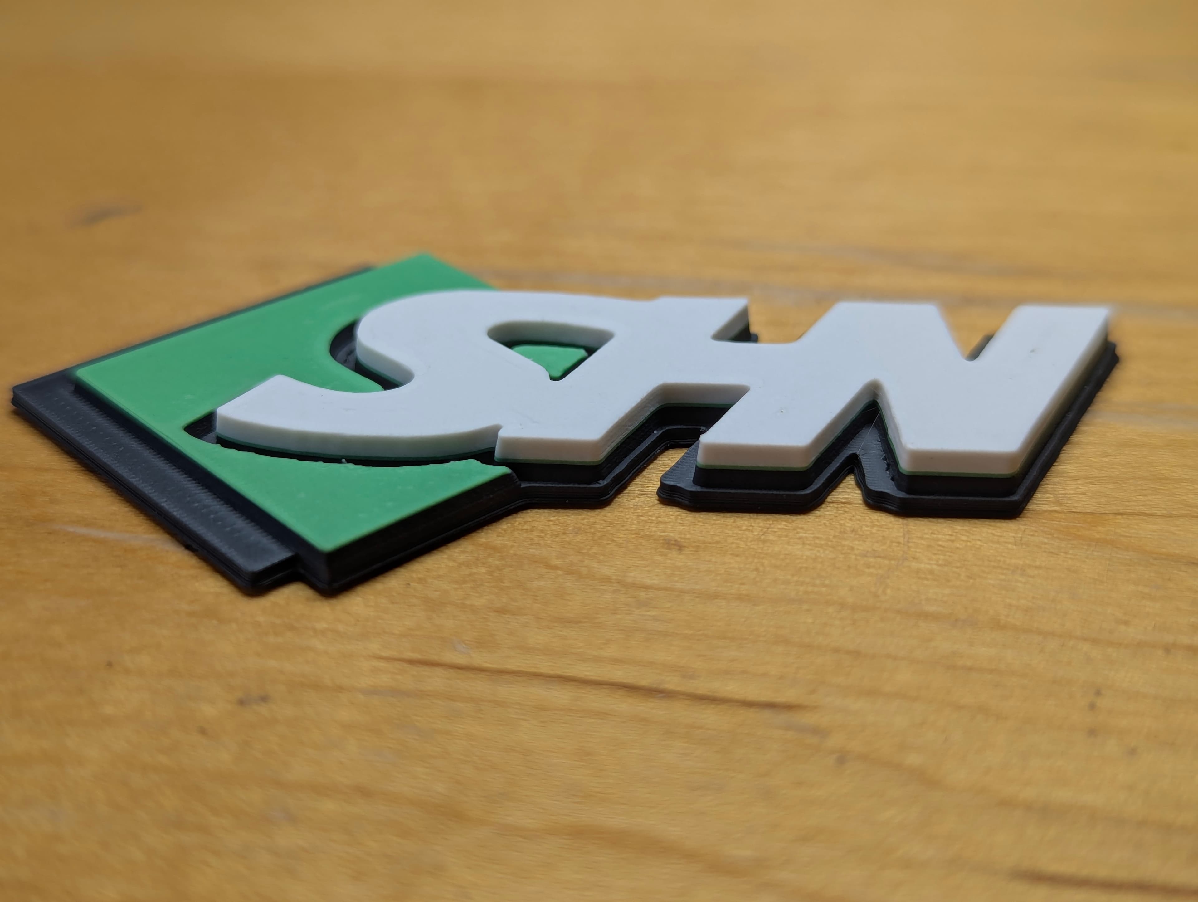 Business logo printed in multi-color filament — dramatic angle showing layered depth