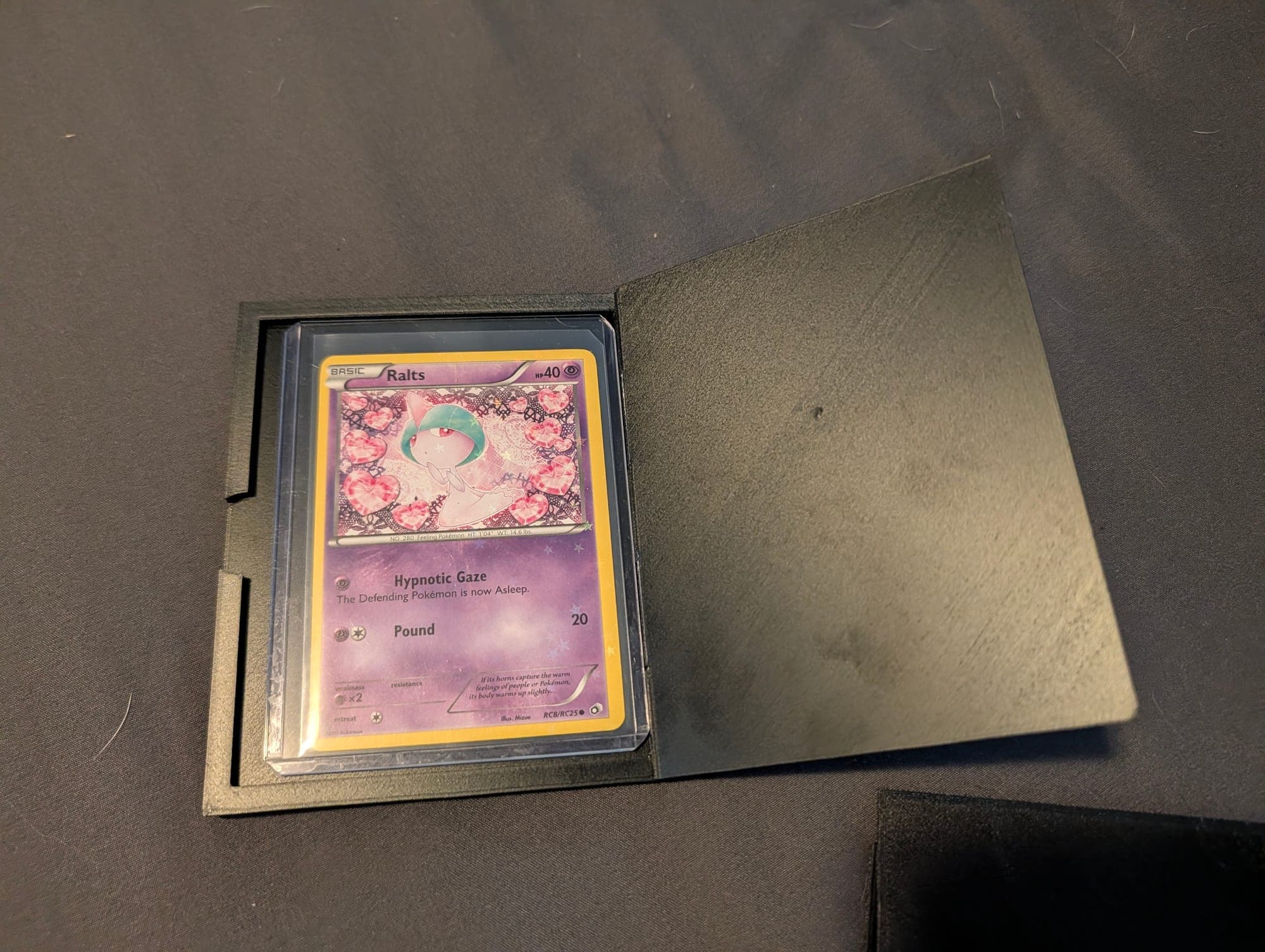Olive card display case open, holding a Pokémon card in a toploader